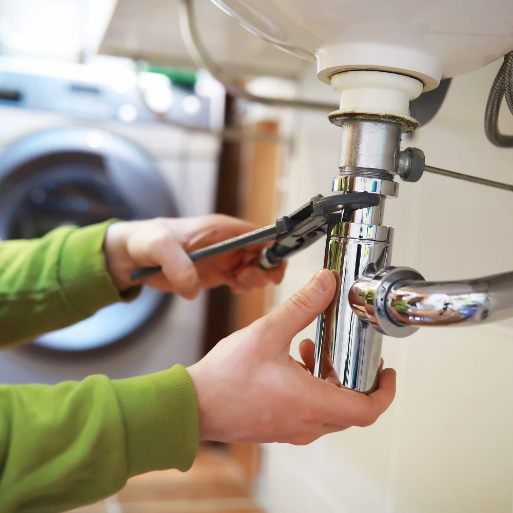 Plumber tightening a sink drain pipe